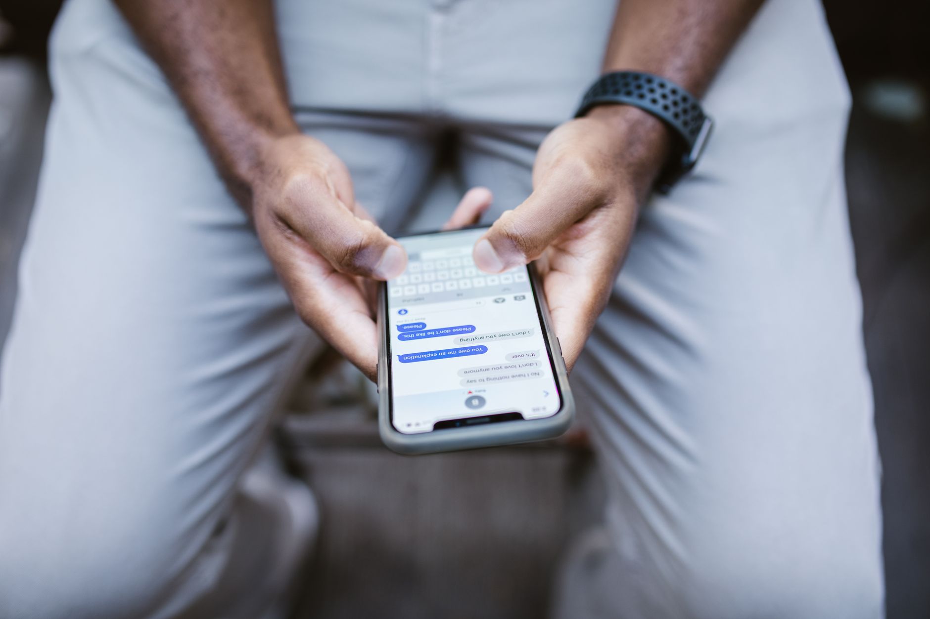 Gros plan sur les mains d'une personne tenant un smartphone et écrivant un message texte.