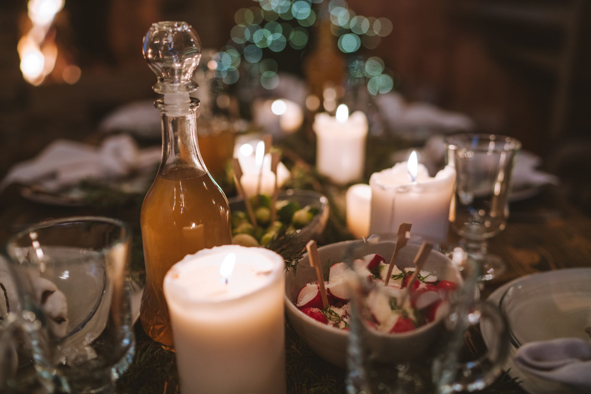 Une table de dîner chaleureuse éclairée par des bougies avec une carafe et un bol de radis.
